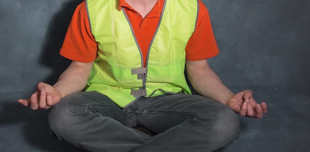 Man wearing a high vis vest doing yoga - demonstrating what a wellness initiative might include